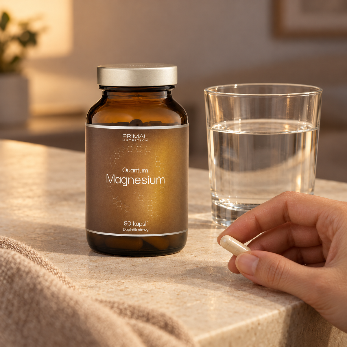 Kapsle v ruce vedle lahvičky Quantum Magnesium a sklenice vody